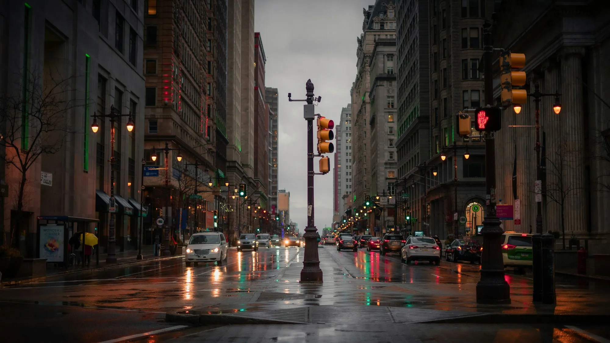 Calle del centro de Filadelfia con lluvia, semáforos y coches entre edificios altos