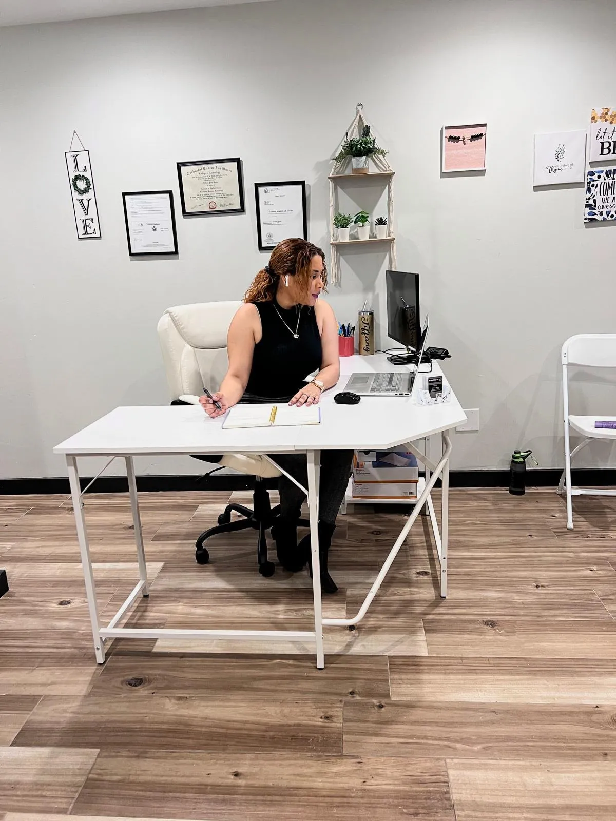 Tiffany Piña trabaja en un escritorio blanco, en una oficina en casa con diplomas enmarcados en la pared